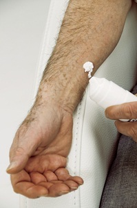 Man applying a skin cream containing testosterone used to replace this sex hormone in men who have lost their sex drive, or had their testes removed due to cancer or other diseases.